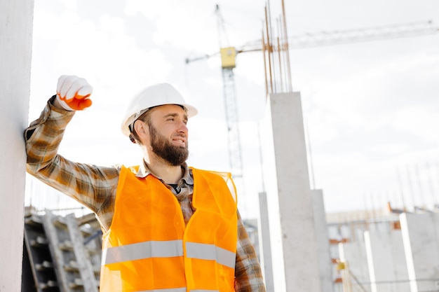 Capataz de reparador de construtor em capacete de segurança e colete trabalha em seu local de trabalho em um prédio em construção