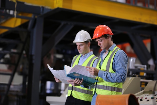 El capataz o el trabajador trabajan en el sitio de la fábrica revisando la máquina o los productos en el sitio Ingeniero o técnico revisando el material o la máquina en la planta industrial y la fábrica