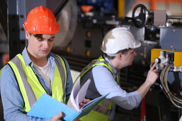 El capataz o el trabajador trabajan en el sitio de la fábrica revisando la máquina o los productos en el sitio Ingeniero o técnico revisando el material o la máquina en la planta industrial y la fábrica