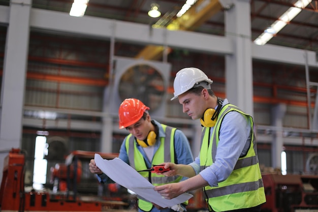 El capataz o el trabajador trabajan en el sitio de la fábrica revisando la máquina o los productos en el sitio Ingeniero o técnico revisando el material o la máquina en la planta industrial y la fábrica