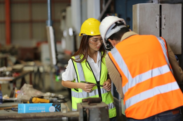 El capataz o el trabajador trabajan en el sitio de la fábrica revisando la máquina o los productos en el sitio Ingeniero o técnico revisando el material o la máquina en la planta industrial y la fábrica