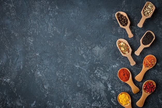 Capítulo de diversas especias en la tabla de piedra oscura. Especias de colores, vista superior. Comida orgánica, estilo de vida saludable.