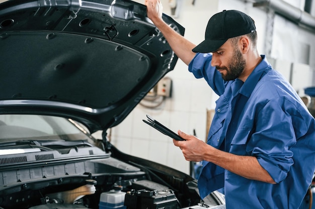 El capó está abierto. Mecánico de automóviles trabajando en el garaje. Servicio de reparación.