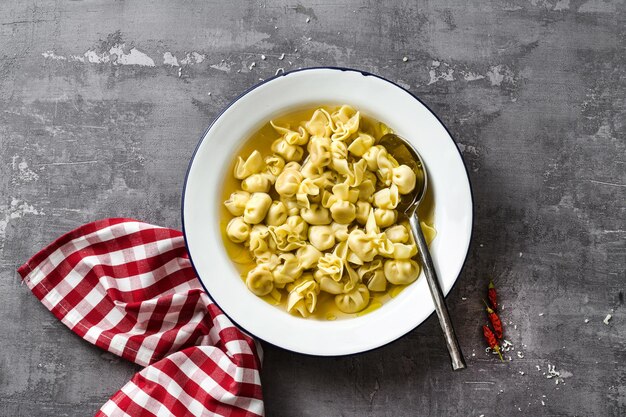 Cappelletti en brodo plato italiano para vacaciones familiares en la mesa con parmesano