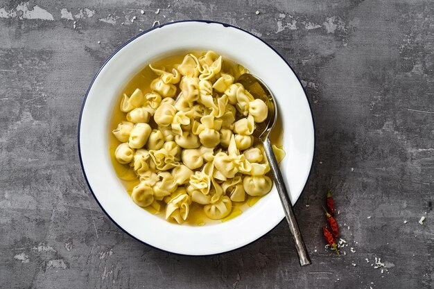 Cappelletti en brodo plato italiano para vacaciones familiares en la mesa con parmesano