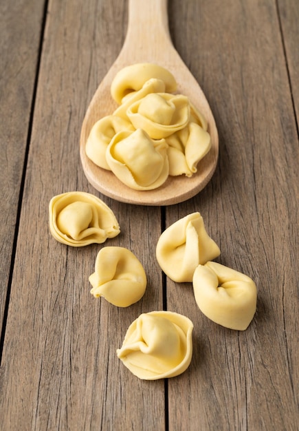 Cappelletti cru ou tortellini em uma colher sobre a mesa de madeira