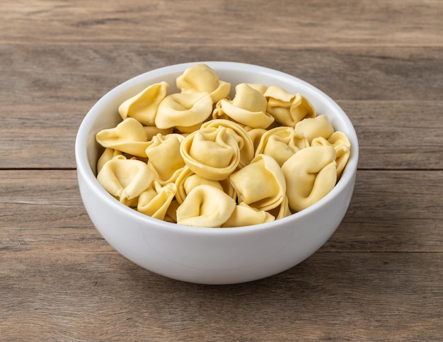 Cappelletti o tortellini crudos en un bol sobre una mesa de madera