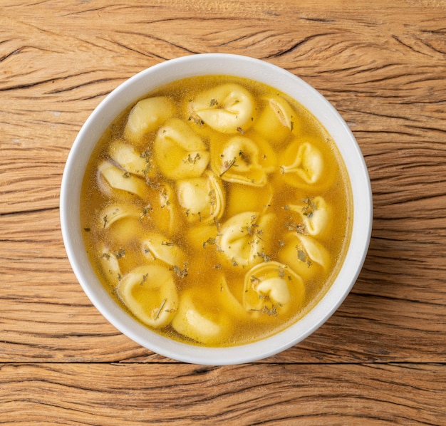 Cappelletti oder Tortellini-Brodo-Suppe in einer Schüssel über Holztisch