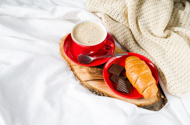 Cappuccino, Chocolate e Croissant em uma cama.