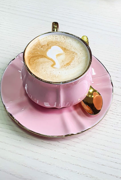 Cappuccino com espuma em uma xícara rosa em uma mesa leve Descanse no café