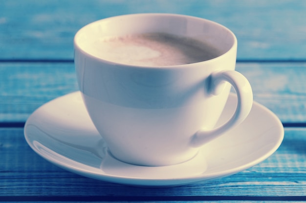 cappuccino em uma caneca branca na mesa azul