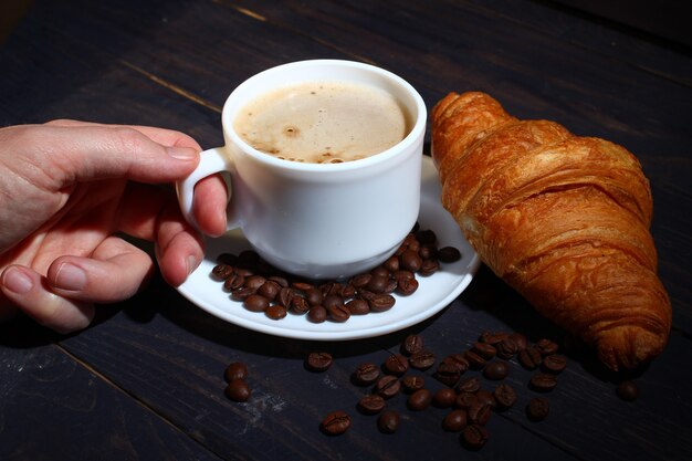 Cappuccino em uma xícara e croissant. Café da manhã popular.