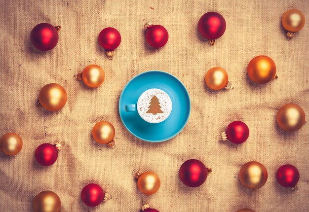 Cappuccino con forma de árbol de navidad y con bolas de navidad rojas y doradas.