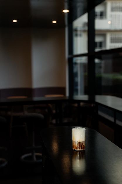 Cappuccino gelado em uma mesa preta com creme sendo derramado, mostrando sua textura.