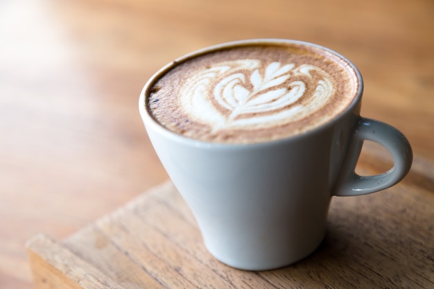 Cappuccino in Weißglas mit Drahtziehen auf Milchschaum.