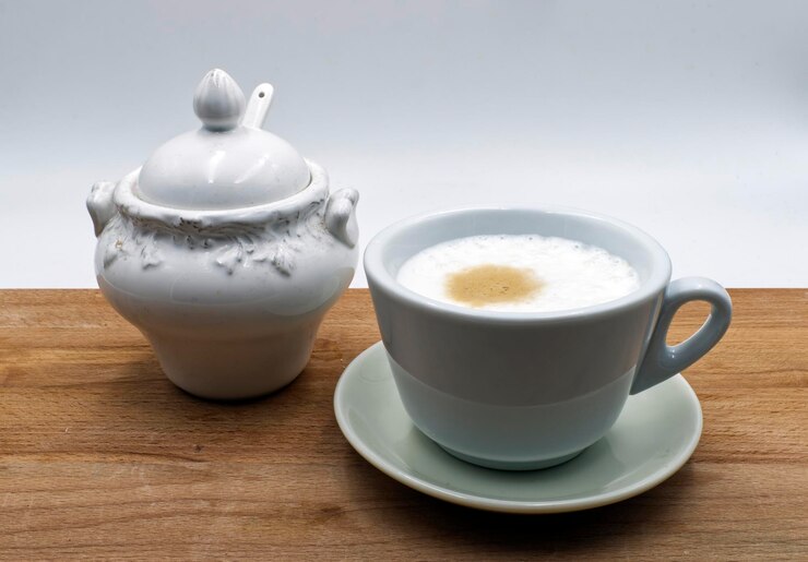 Foto cappuccino italiano com tigela de açúcar de cerâmica em mesa de madeira com fundo branco