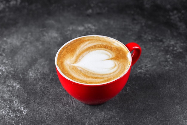 Cappuccino-Kaffee in einer roten Tasse auf grauem Beton mit Platz für Text