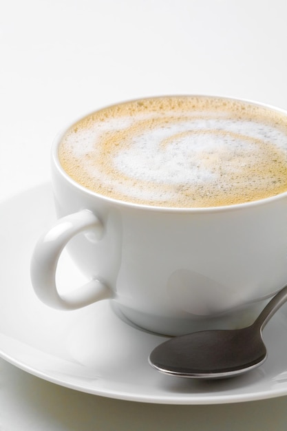 Cappuccino-Kaffee in weißer Kaffeetasse mit Untertasse und Löffel