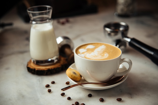 Cappuccino-Kaffee zum Frühstück mit Milch und Keksen auf einem weißen Marmortisch