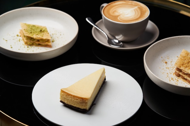 Cappuccino Kaffeetasse und Kuchen auf Teller auf Tisch, Nahaufnahme.