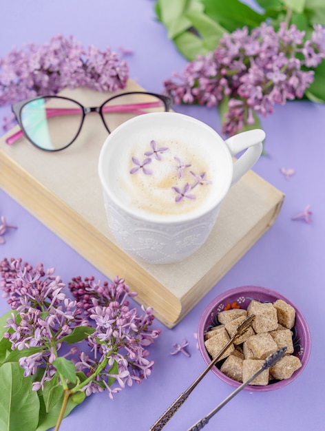 Cappuccino, libro con gafas y flores lilas violetas