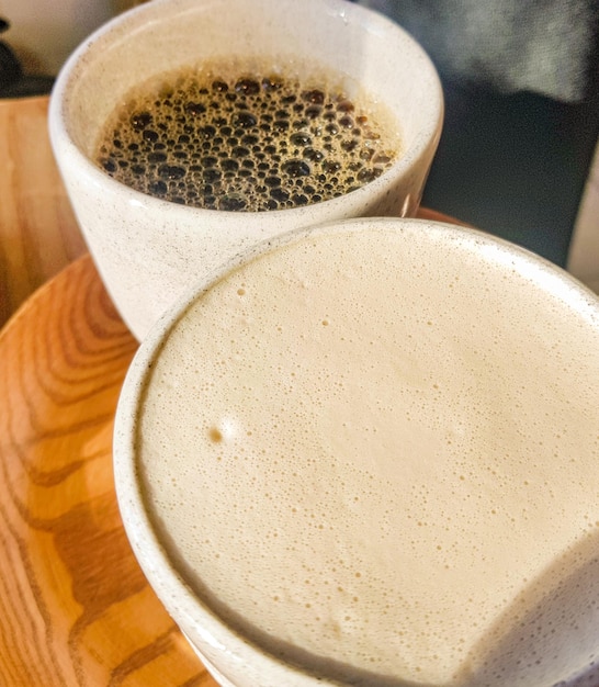 Cappuccino mit duftendem Milchschaum und schwarzem Americano auf einem Holztablett Blick von oben Kaffee zu zweit Köstlicher frisch gebrühter Kaffee zum Frühstück im Café