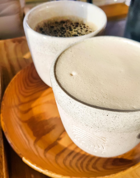 Cappuccino mit duftendem Milchschaum und schwarzem Americano auf einem Holztablett Blick von oben Kaffee zu zweit Köstlicher frisch gebrühter Kaffee zum Frühstück im Café