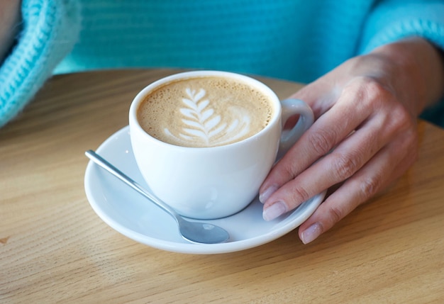 Cappuccino na mesa. A garota está tomando café em um café.