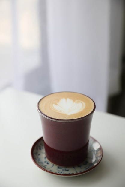 Cappuccino o café Latte art hecho con leche en la mesa de madera en la cafetería.