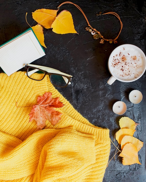 Cappuccino, óculos e um suéter amarelo brilhante estão no escuro