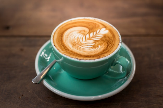 Cappuccino quente com latte art em fundo de madeira