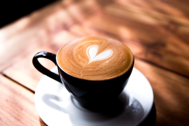 Cappuccino-Tasse mit Herz-Latte-Art auf Holztischhintergrund