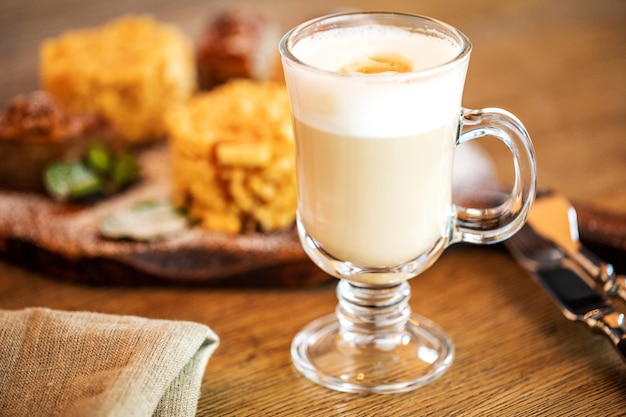 Cappuccino-Tasse mit Latte auf Holzhintergrund Schöne schaumgrüne Keramiktasse