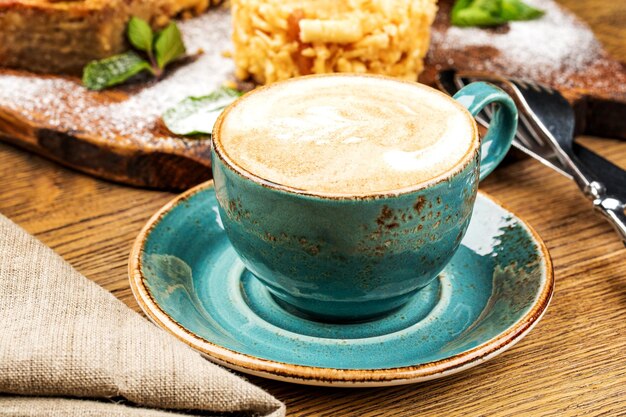 Cappuccino-Tasse mit Latte auf Holzhintergrund Schöne schaumgrüne Keramiktasse
