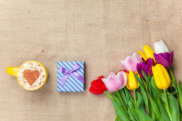 Cappuccino und Geschenkbox nahe Blumen