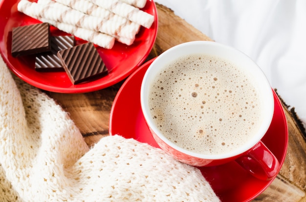 Cappuccino und Schokolade auf einem Bett mit Plaid.