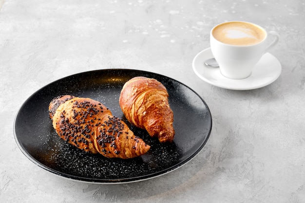 Cappuccino und zwei Croissants auf einem Tisch