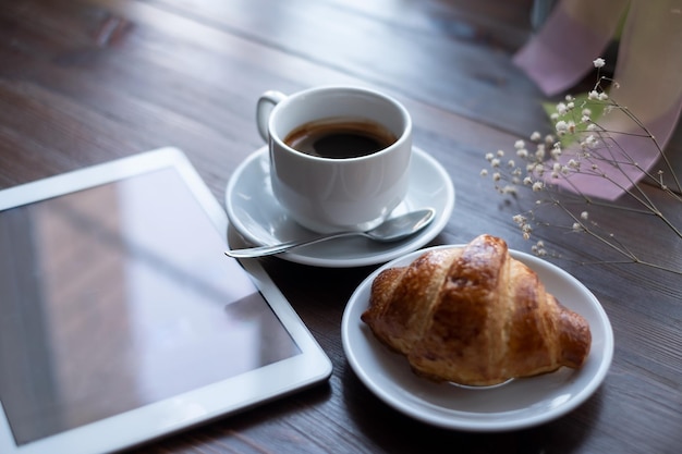 Cappuchino com croissant close-up com tablet