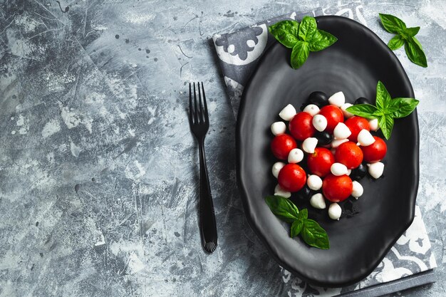 Foto caprese com tomates cereja mini mozzarella folhas frescas de manjericão antipasto de comida italiana tradicional