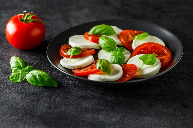 Caprese italiano antepasto mussarela tomate e manjericão no fundo escuro vista lateral foco seletivo