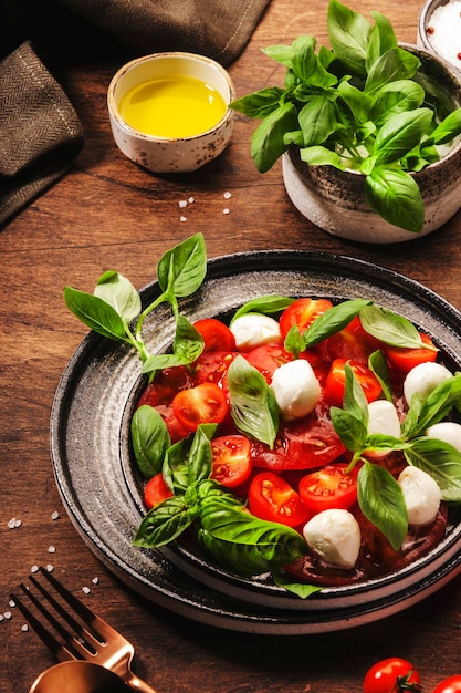 Caprese italienischer Salat mit roten Tomaten und Mozzarella-Käse mit grünen Basilikumblättern Draufsicht Holztisch