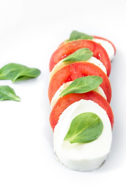 Foto caprese-salat auf einem grauen teller mit basilikumblättern isoliert