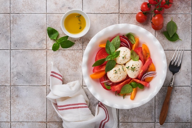 Caprese-Salat Italienischer Caprese-Salat mit in Scheiben geschnittenen Tomaten Mozzarella-Käse-Basilikum-Olivenöl in weißen Teller auf weißem Hintergrund Leckeres italienisches Essen Draufsicht Rustikaler Stil