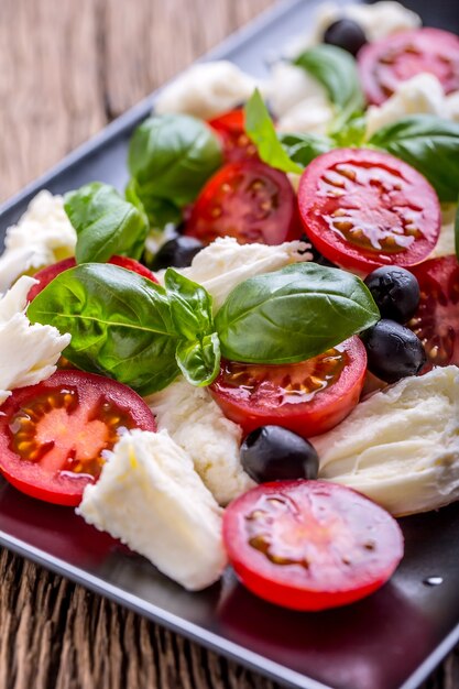 Caprese Salat Mediterraner Salat Mozzarella Kirschtomaten Basilikum und Olivenöl auf altem Eichentisch