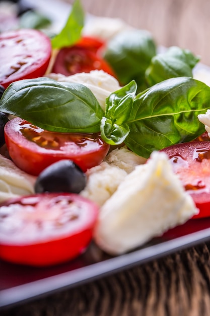 Caprese Salat Mediterraner Salat Mozzarella Kirschtomaten Basilikum und Olivenöl auf altem Eichentisch
