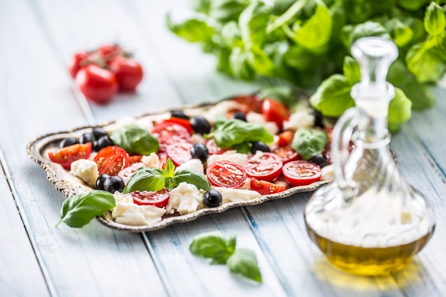 Caprese-Salat mit Mozzarella-Käse, reifen Tomaten, Oliven und Basilikumblättern. Italienische oder mediterrane gesunde Mahlzeit.