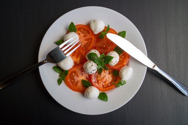 Caprese-Salat mit reifen Tomaten und Mozzarella mit frischen Basilikumblättern. Italienisches Essen.