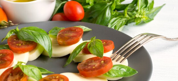 Caprese-Salat mit reifen Tomaten und Mozzarella mit frischen Basilikumblättern. Italienisches Essen.