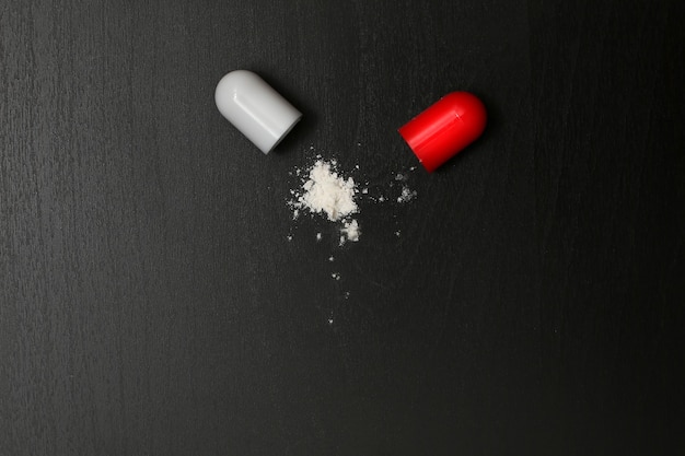 Cápsula com comprimido medicinal em pó aberto borrifando antibiótico de ingrediente ativo medicinal branco