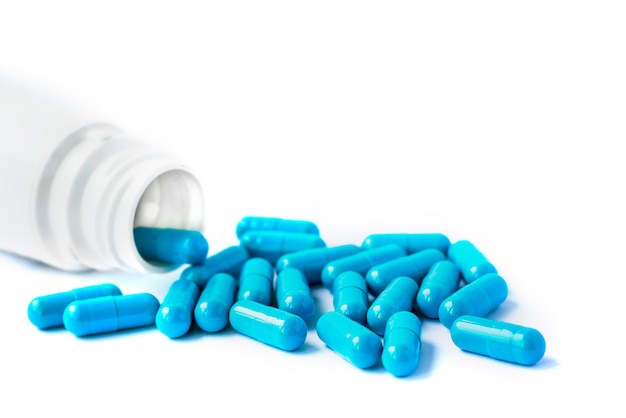 Cápsulas azules, píldoras aisladas sobre fondo blanco con espacio de copia. Cápsulas en un frasco blanco.